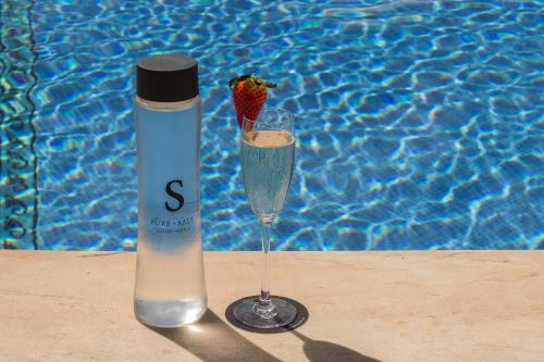 a bottle of water and a strawberry in a wine glass at Pure Salt Port Adriano - Adults Only in Santa Ponsa