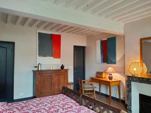 a bedroom with a bed and a table with a chair at La ferme des douceurs in Cervon