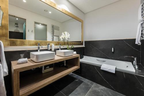 a bathroom with two sinks and a tub and a mirror at Pure Salt Port Adriano - Adults Only in Santa Ponsa