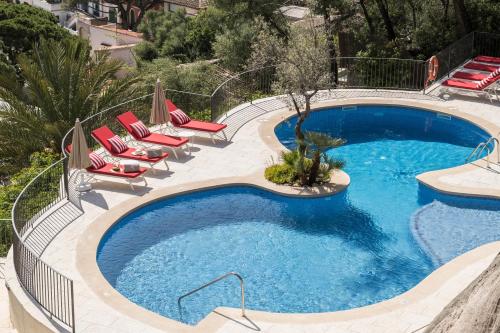 a swimming pool with red lounge chairs and a swimming pool at Pure Salt Port de Sóller in Port de Soller