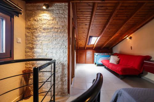 a living room with a red couch and a brick wall at Delmare Olive beach house II in Yerakiní