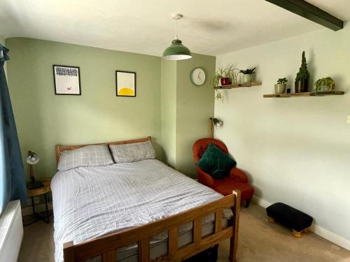 1 dormitorio con 1 cama y 1 silla roja en Quiet & Cosy 2-Bedroom Cottage in Coltishall en Coltishall