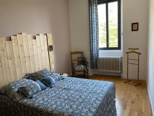a bedroom with a bed with a blue comforter and a window at Gite des voyageurs in Villefort