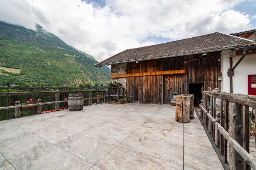 a large patio in front of a barn with mountains at Sagschneiderhof Golden Delicious in Plaus