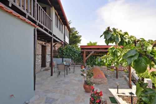 a patio with tables and chairs and a building at To Patriko Mas Guesthouse-2 in Palaios Panteleimonas
