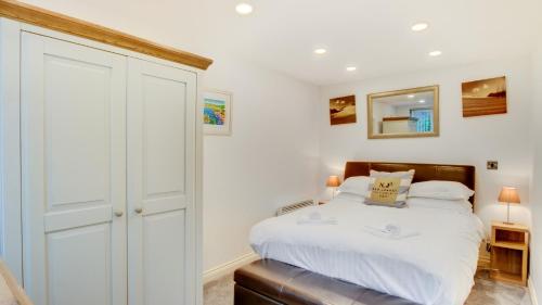 a white bedroom with a bed and a closet at Limeslade Court in The Mumbles