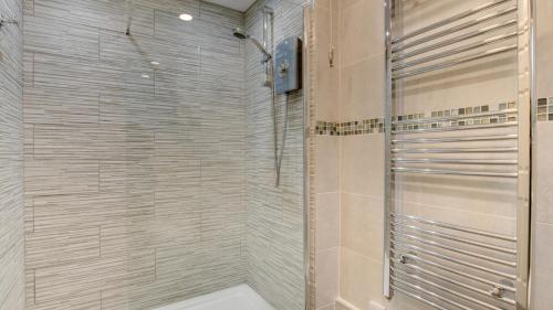 a shower with a glass door in a bathroom at Limeslade Court in The Mumbles