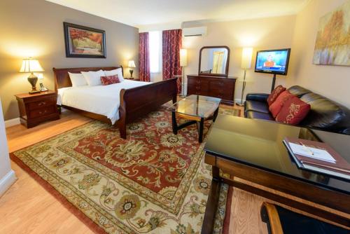 a bedroom with a bed and a living room with a couch at Norwalk Inn & Conference Center in Norwalk