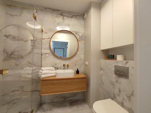 uma casa de banho com um lavatório e um espelho em Woronicza Premium Apartments - 80 em Varósvia