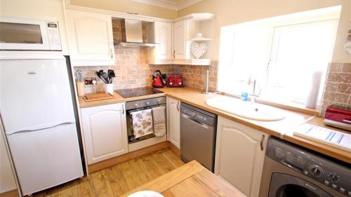 uma cozinha com um frigorífico branco e um lavatório em Coastal View em Oxwich