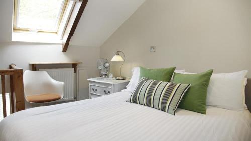 a bedroom with a white bed with green pillows at Llethryd Farm Cottage Two in Llanmorlais