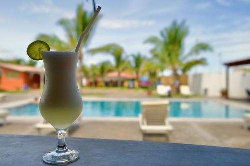 a drink with a lime on a table next to a pool at ÓRGANOS BEACH bungalows & suites in Los Órganos