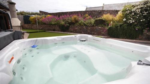 a jacuzzi tub in a backyard with flowers at Glebe Farm in Rhossili