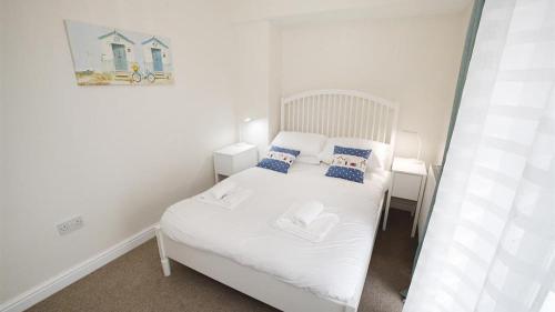 ein kleines Schlafzimmer mit einem weißen Bett mit blauen Kissen in der Unterkunft Delfryn Cottage in The Mumbles