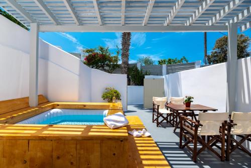 un patio con piscina, mesa y sillas en Aerenia Luxury Suites en Karterados