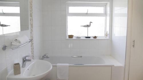 ein weißes Badezimmer mit einer Badewanne und einem Waschbecken in der Unterkunft Westbourne Place in The Mumbles