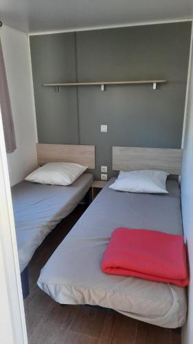 Duas camas num quarto com um cobertor vermelho em MobilHome de Charlotte - Camping La Falaise 4 étoiles em Narbonne Plage