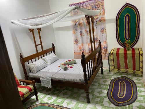 a bedroom with a bed with a canopy and a chair at Sanaa Hostel in Zanzibar City