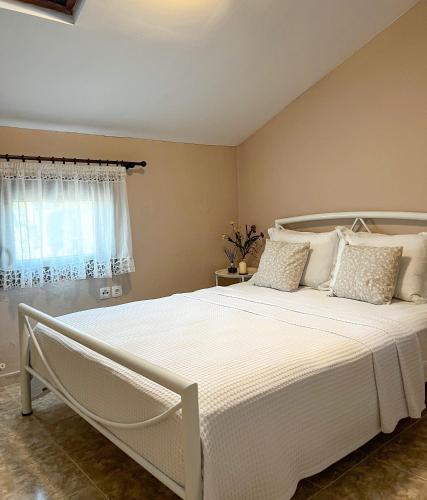 Aktaia Villa في إيريسوس: سرير أبيض في غرفة نوم مع نافذة