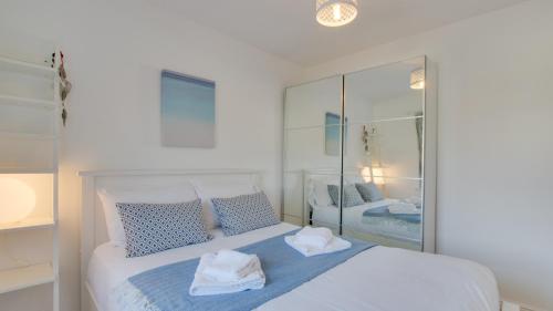 1 dormitorio con cama blanca con almohadas azules y espejo en William Gammon Dr, en Mumbles