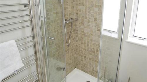 een douche met een glazen deur in de badkamer bij Westfields in Nicholaston