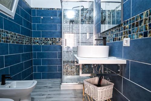 uma casa de banho com paredes em azulejos azuis e um lavatório. em Mencin em Carloforte