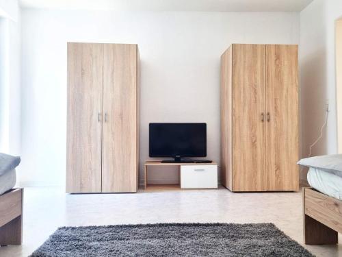 a bedroom with two wooden cabinets and a television at Fully equipped Apartment with big balcony and cozy living room in Dietzenbach
