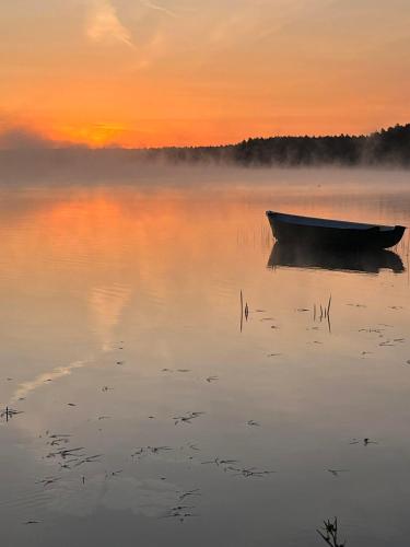 a boat sitting in the water at sunset at Domek w Gruszkach in Gruszki