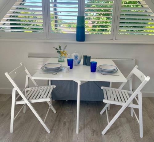 a white table with two chairs and a table with plates at Cosy accommodation, easy walk to beach! in Barton on Sea