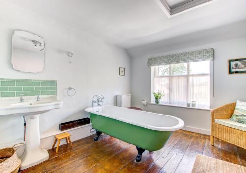 uma casa de banho com uma banheira verde e um lavatório em Brook Farm Walpole em Walpole
