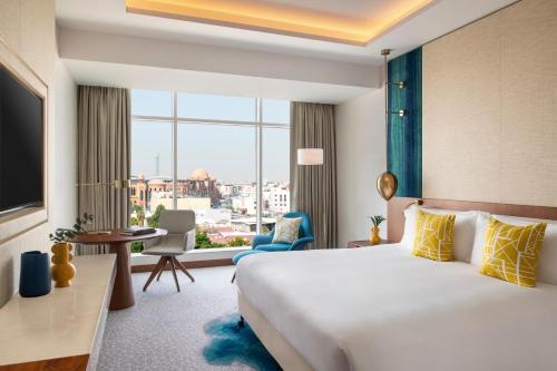 a hotel room with a bed and a large window at Abesq Doha Hotel and Residences in Doha