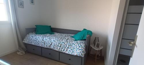 - un petit lit avec 2 oreillers verts dans l'établissement Bastides du Gd Stade - Appart dans la verdure proche plage - Piscine, à Saint-Cyprien