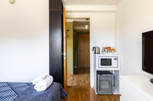 Habitación pequeña con cama y microondas. en Quiet Rum in Swedish villa, en Huddinge