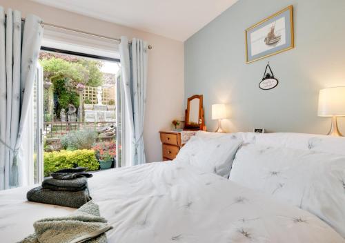 a bedroom with a white bed and a window at Forget-me-not Bungalow in Seaton