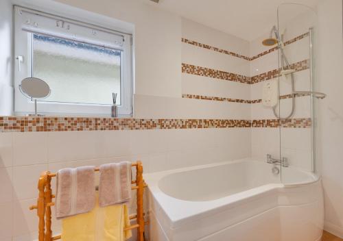 a white bathroom with a tub and a window at Little Hollies in Salcombe Regis