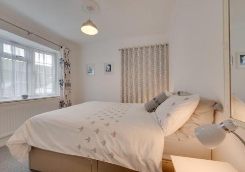 a white bedroom with a bed and a window at Little Hollies in Salcombe Regis
