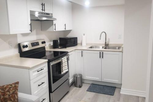 una piccola cucina con armadi bianchi e lavandino di An Ideal Apartment for you. a Brampton