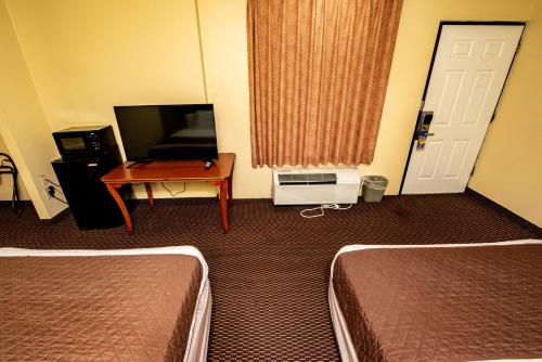 a hotel room with two beds and a television at River Place Inn in Pigeon Forge