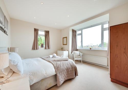 a white bedroom with a large bed and a window at Tay Craig in Sidmouth