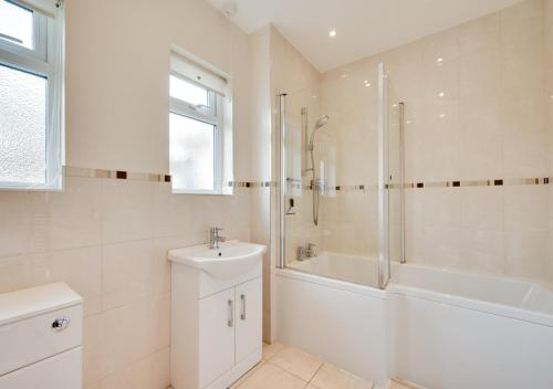 a white bathroom with a shower and a sink at Tay Craig in Sidmouth