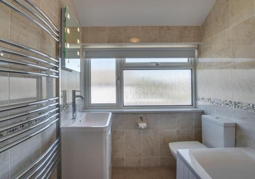 baño con lavabo y aseo y ventana en Puffins, en Paignton