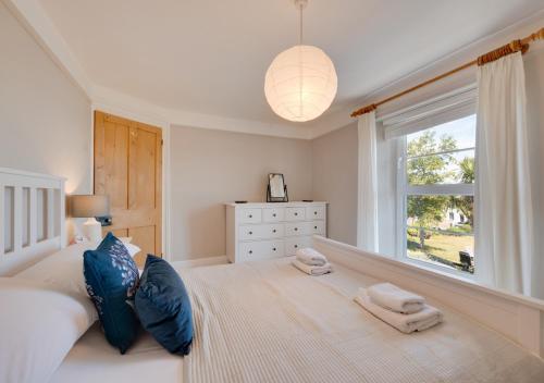 a bedroom with a large bed with blue pillows and a window at April Cottage in Brixham