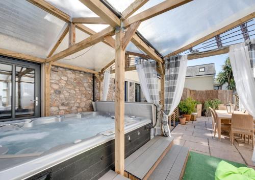 a large hot tub in a patio with a table at Rutland Lodge in Torquay