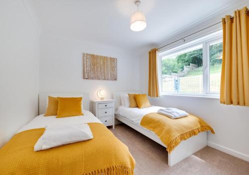 two beds in a bedroom with a window at Crows Nest in Brixham