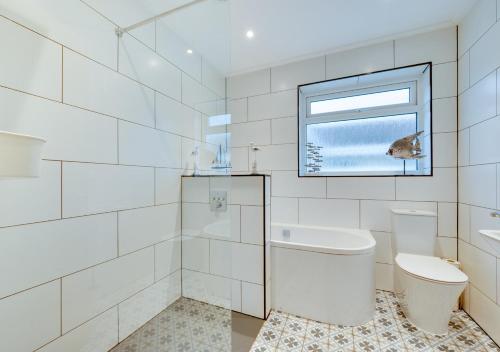 een witte badkamer met een toilet en een raam bij Compass Rose in Brixham