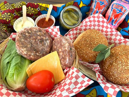 a tray of food with hamburgers and vegetables and sauce at High Season Farm Luxury Cottages in Hermanus