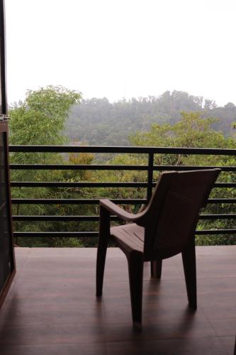 a chair sitting on a porch with a view at Coorg Nature Breeze home stay in Madikeri