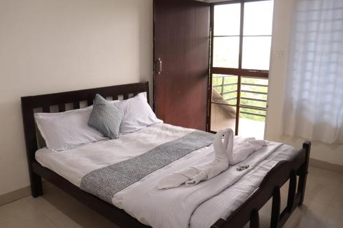 a bed with a towel on it with a window at Coorg Nature Breeze Homestay in Madikeri