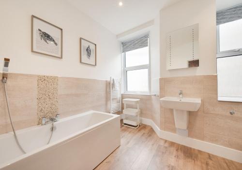 a white bathroom with a tub and a sink at 2A Riverview - Top Flat in Dartmouth