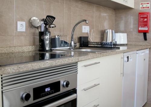 a kitchen with a sink and a stove at Cabo do Mar Apart- Azul Beach in Espinho